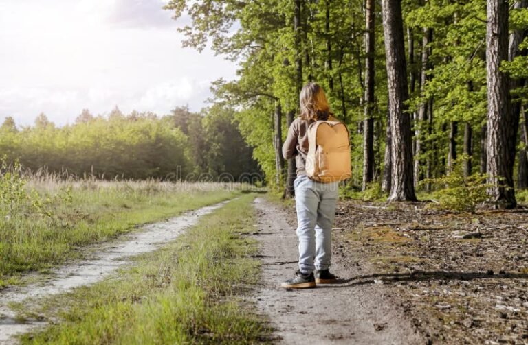 nino con mochila caminando por sendero natural